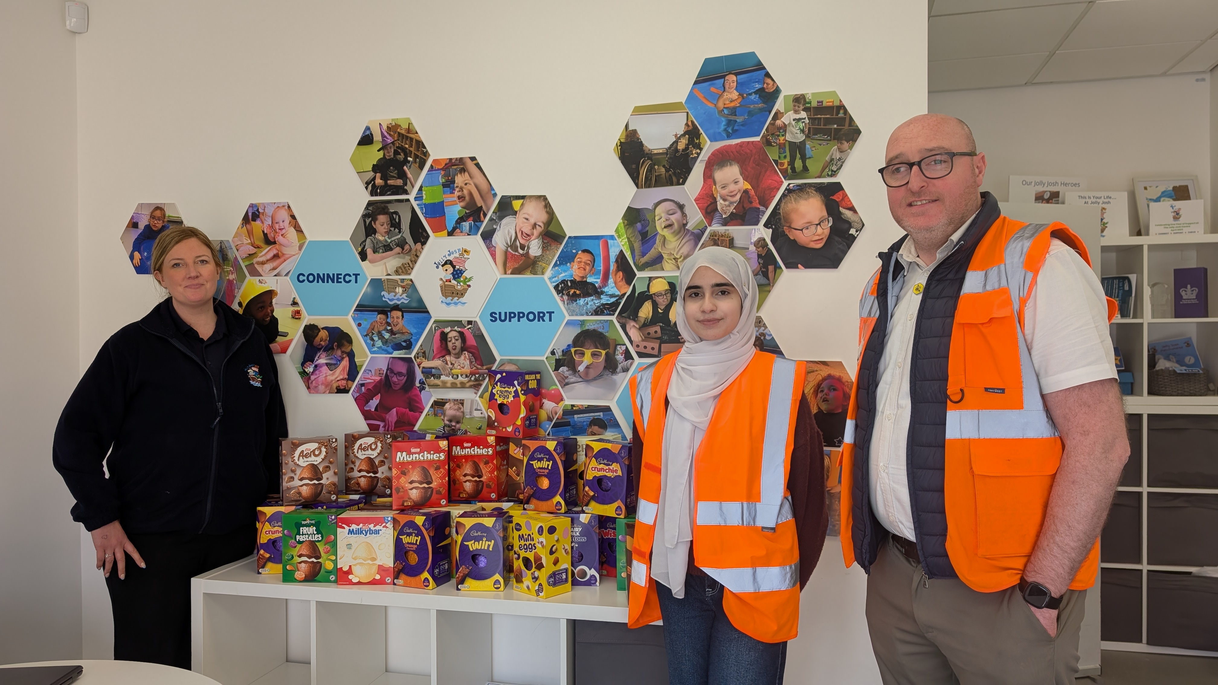 Three people standing by a display of chocolate easter eggs.