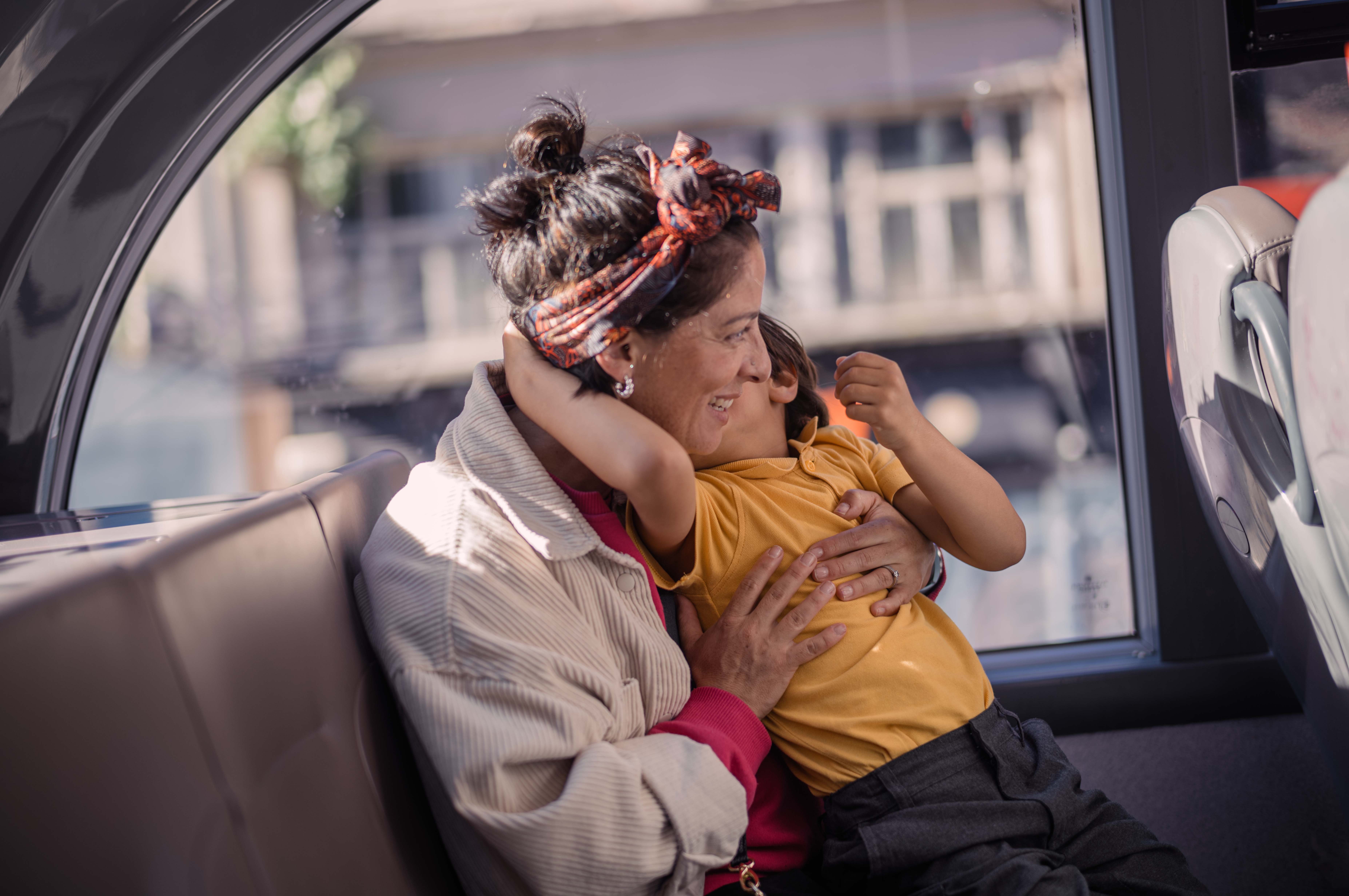 Mother and child cuddling whilst looking out of a bus window