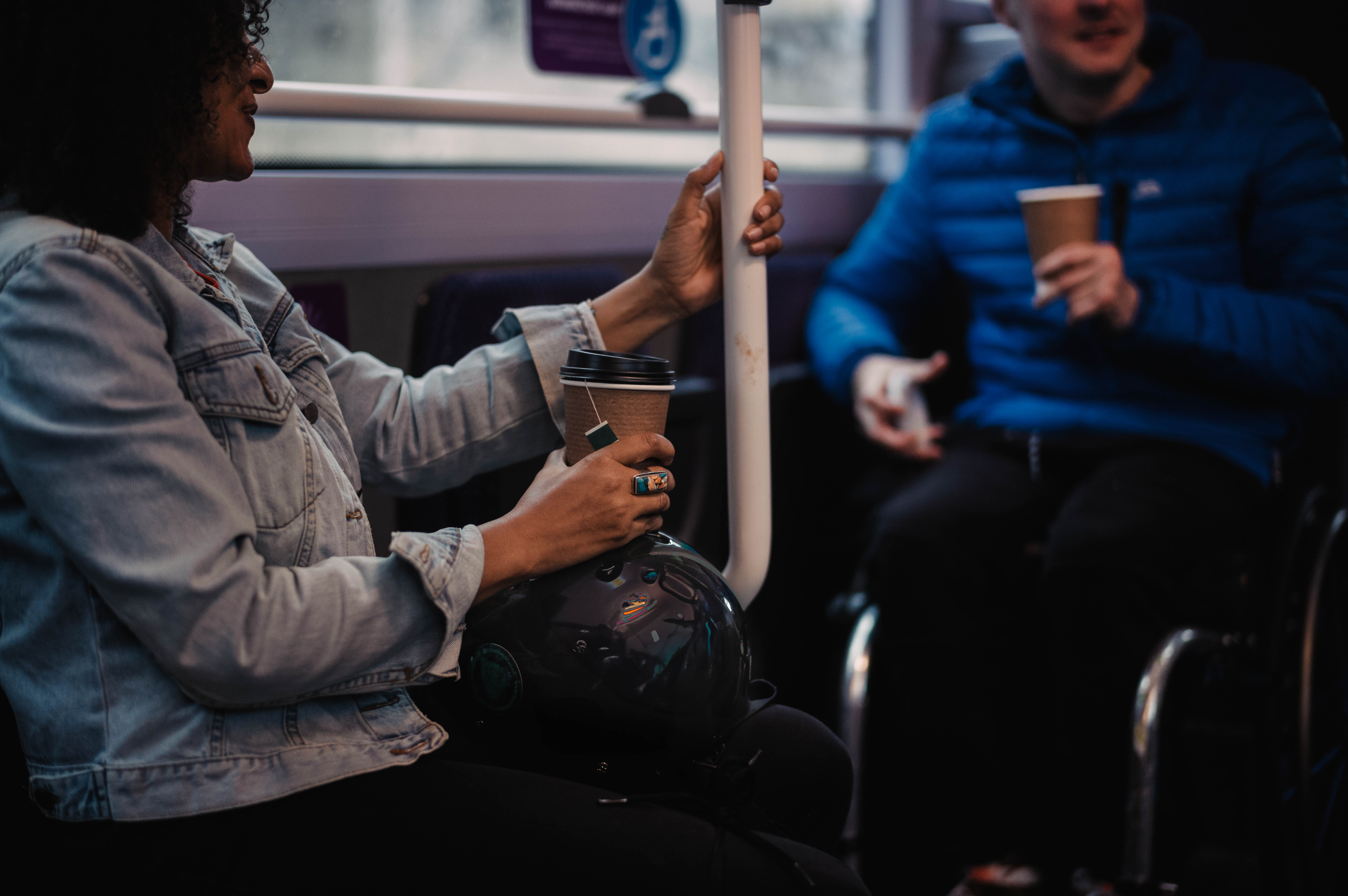 People holding hot drinks on board a bus