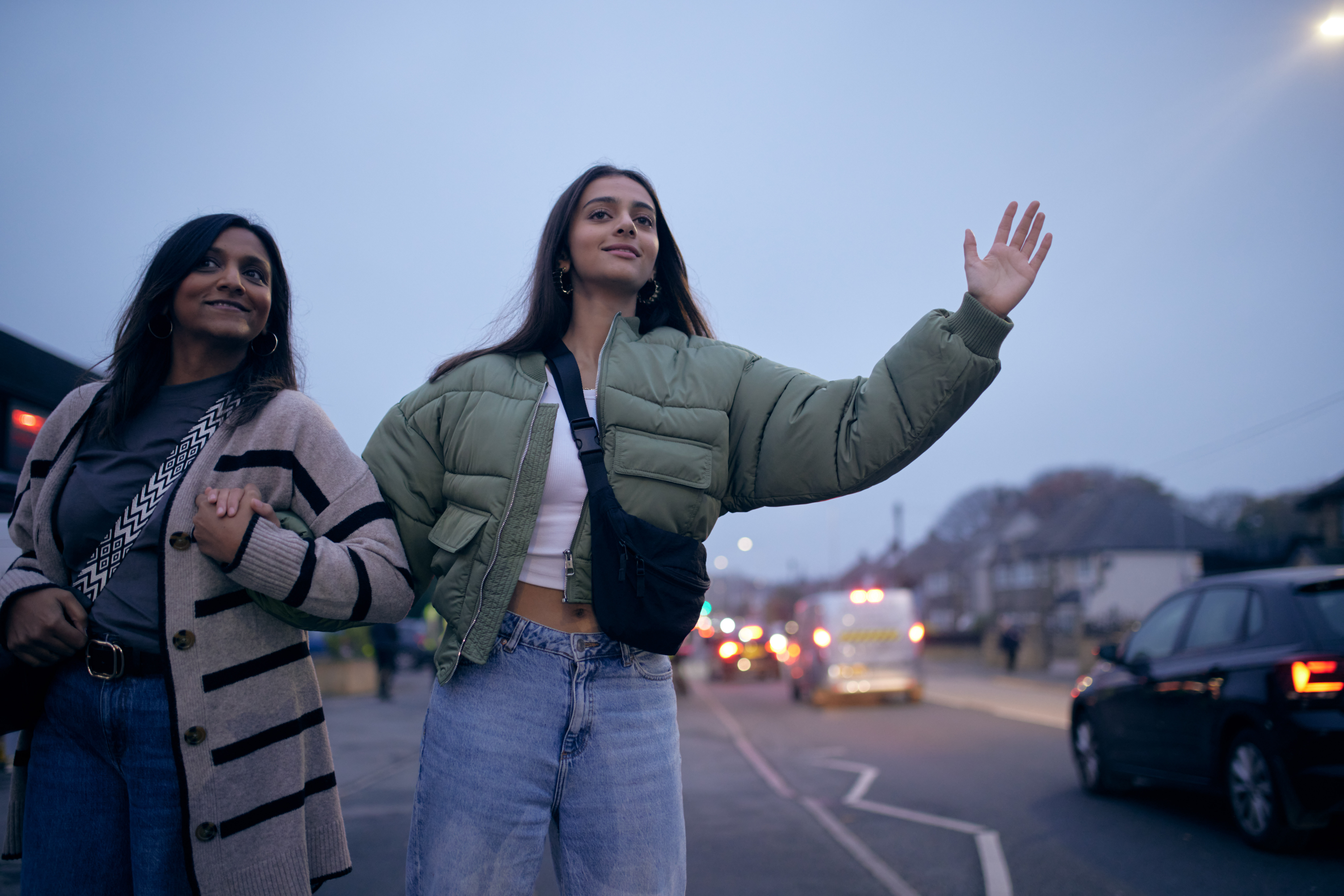 2 people waiting for the bus and holding their arm out