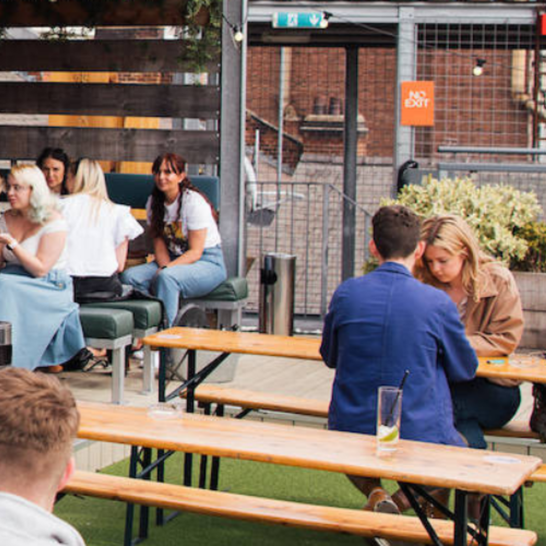 People at tables outside on top of a building
