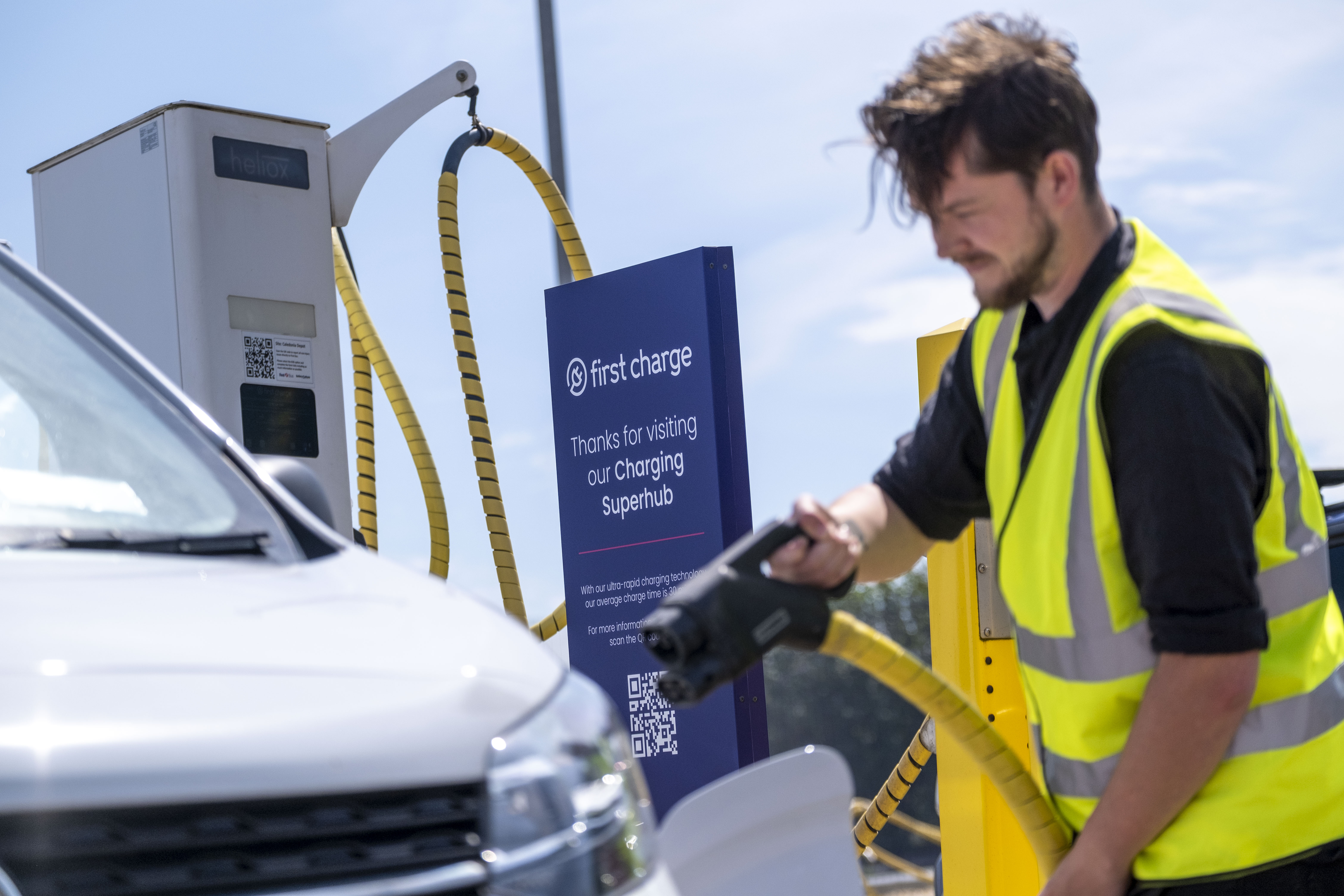 man in hi-vis holding charger to van