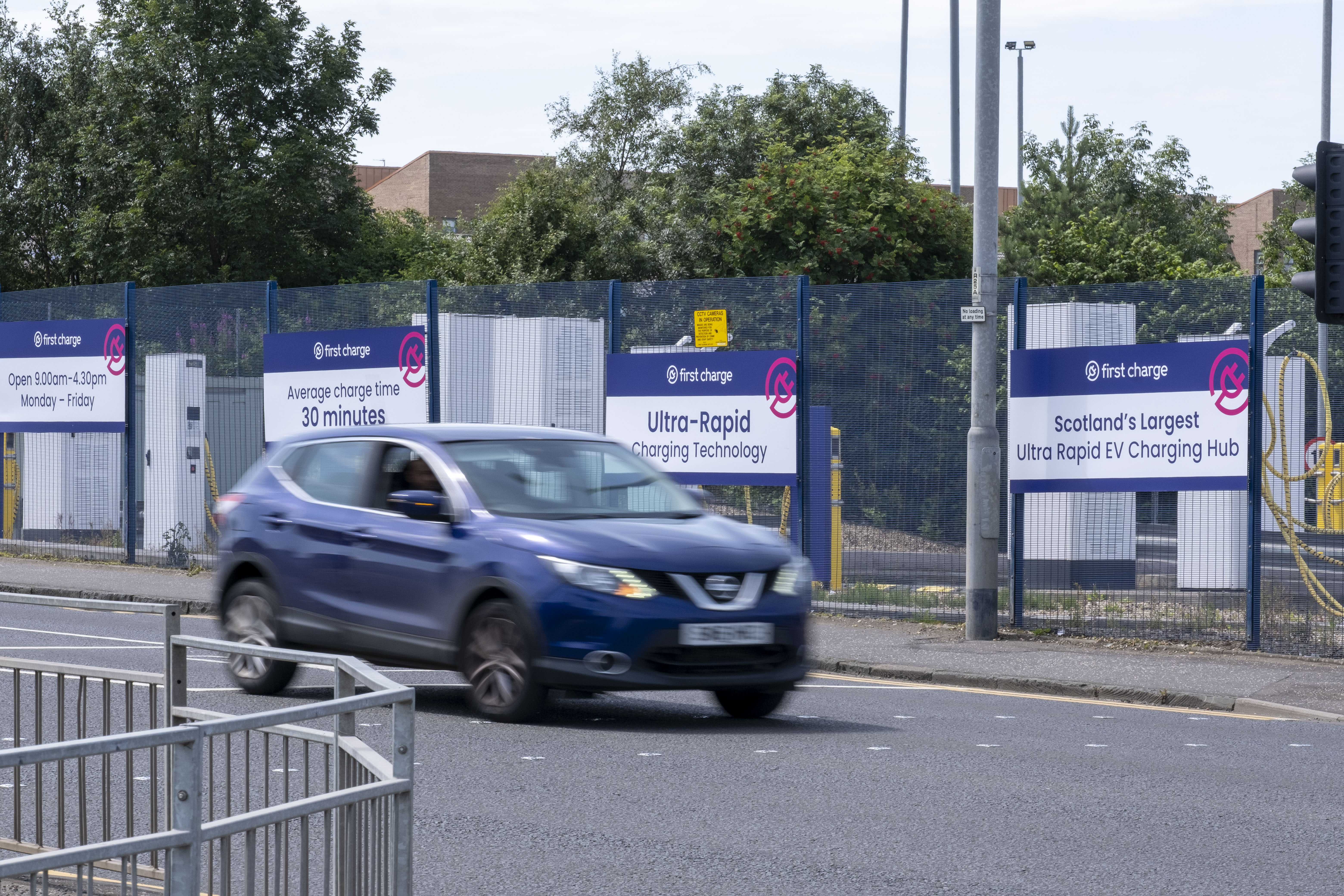 car on road passing first charge signage