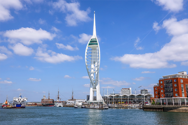A wide shot of spinnaker tower with the sea in front and boats surrounding
