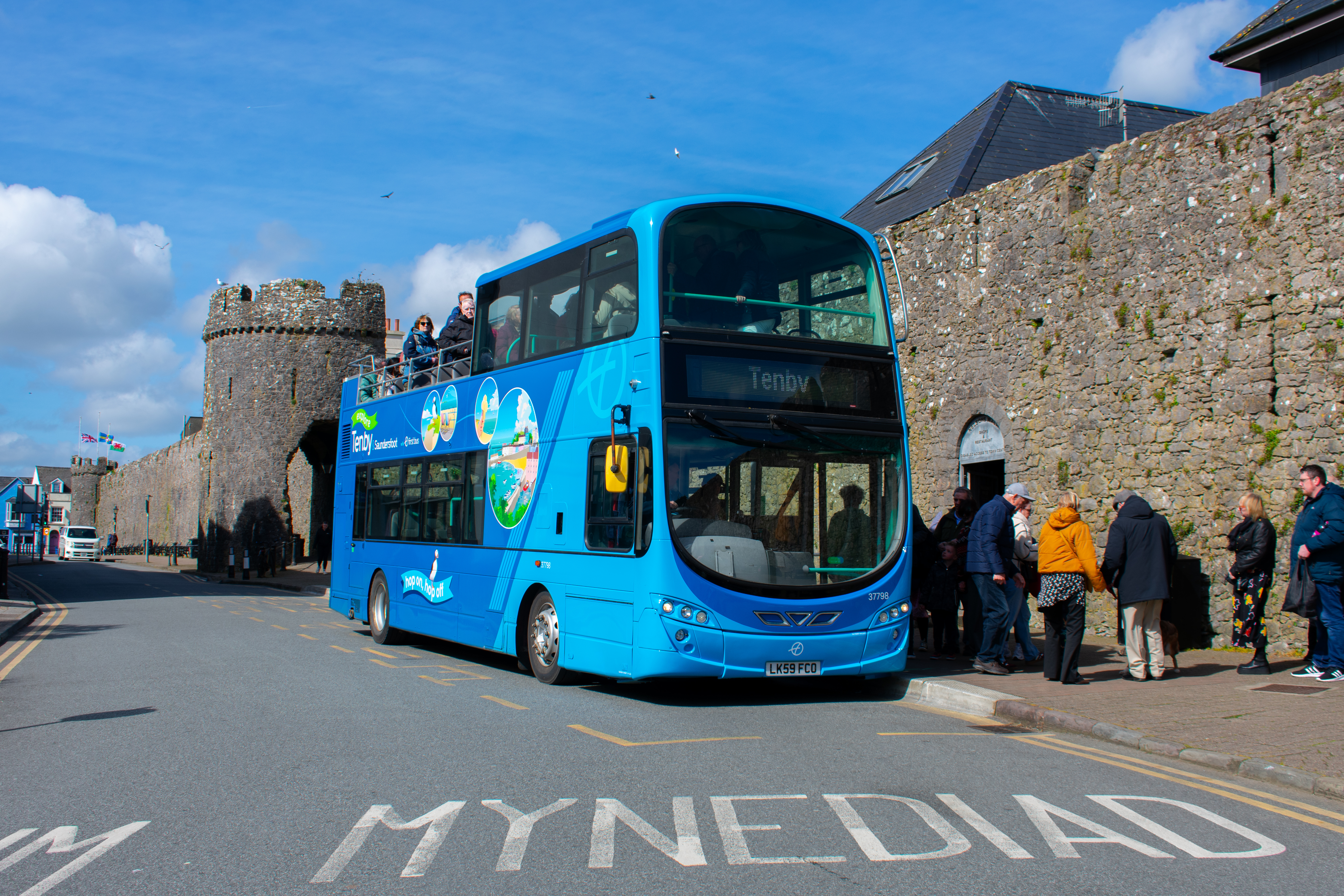 an open-top bus at the bus stop in Tenby